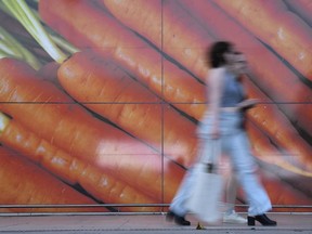 FILE - Shoppers walk past a large poster outside a supermarket in London, on June 10, 2023. Inflation in the U.K. held steady at 4% in January as lower food prices helped offset an increase in energy costs, official figures showed Wednesday, Feb. 14, 2024. The reading was better than expected as most economists expected inflation to rise modestly to around 4.2%. The Office for National Statistics said the monthly drop in food prices of 0.4% was the first since September 2021.