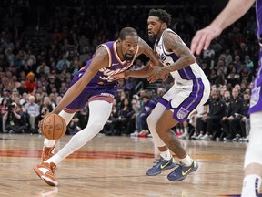 Phoenix Suns' Kevin Durant drives around Sacramento Kings' Malik Monk during the second half of an NBA basketball game in Phoenix, Tuesday, Feb. 13, 2024.