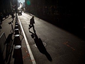 Pedestrians walk along Wall Street