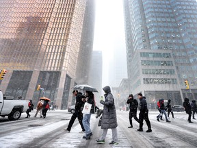 Pedestrians walk across Front Street at Bay Street in Toronto's financial district.