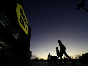 FILE - People are silhouetted against the sky at dawn as they attend a sale at a Best Buy store Friday, Nov. 25, 2022, in Overland Park, Kan. Best Buy reported lower fourth-quarter sales and net income, Thursday, Feb. 29, 2024, as shoppers remain cautious about spending on gadgets.