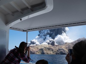 FILE - In photo provided by Michael Schade, tourists on a boat look at the eruption of the volcano on White Island, New Zealand, Dec. 9, 2019. Tour booking agents and managers of a New Zealand island where a volcanic eruption killed 22 people in 2019 were ordered Friday, March 1, 2024 to pay nearly $13 million (US$7.8 million) in fines and reparations.