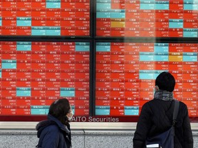 FILE - People look at an electronic stock board showing Japan's stock prices at a securities firm on Jan. 17, 2024, in Tokyo. Asian shares mostly rose Friday, Feb. 2, helped by optimism about technology shares following a Wall Street rally led by big tech stocks.