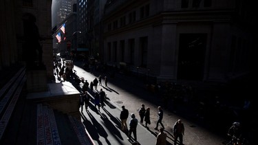 Pedestrians walk along Wall Street