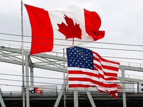Canadian and American flags fly by the Blue Water Bridge crossing from Ontario to Michigan. A strong U.S. economy could mean higher mortgage rates on the northern side of the border.