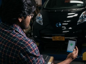 An engineer holds a smartphone displaying the Hevo Inc. application to charge electric vehicles with wireless technology.