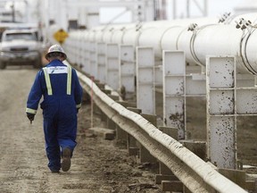 A worker walks along a pipeline at the Enbridge Inc. facility in east Edmonton.