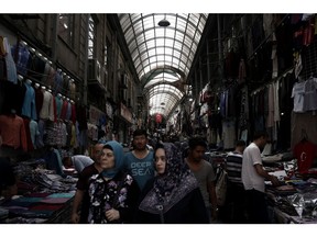 Visitors walk past vendors selling clothing in the Grand Bazaar covered market in the Sultanahmet district of Istanbul, Turkey, on Thursday, Aug. 3, 2017. Turkey's central bank raised its inflation forecast for this year on higher food prices, and reiterated its policy not to loosen monetary conditions until the outlook improves.