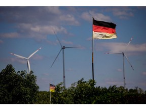 German national flags near wind turbines operated by Salzgitter AG, part of the Salzgitter Low CO2 Steelmaking (SALCOS) green steel project, at the company's mill in Salzgitter, Germany, on Tuesday, July 5, 2022. Salzgitter is looking to transform billowing foundries dating back decades into green steel production in a project to remain viable for years to come and a key test of German industry's ability to transition to cleaner technologies. Photographer: Krisztian Bocsi/Bloomberg