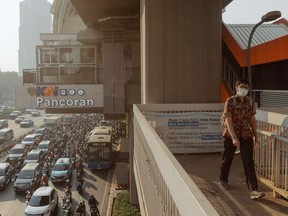 A commuter walks along an overpass in Jakarta, Indonesia, during a weeks-long spike in local air pollution, Aug. 22, 2023.  Photographer: Muhammad Fadli/Bloomberg