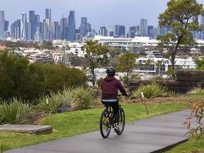 A person cycles past the city skyline in Melbourne.