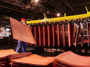 A worker handles newly formed copper cathode sheets in a warehouse at the KGHM Polska Miedz SA copper smelting plant in Glogow, Poland.