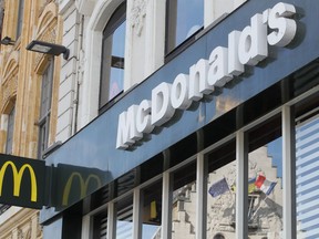 FILE - A French and a European flags are reflected in the shop window of a McDonald's restaurant in Lille, northern France, Thursday, June 16, 2022 . McDonald's will become the title sponsor of the French soccer league from July for the next three seasons, the league said on Thursday, March 21, 2024.
