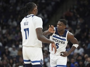 Minnesota Timberwolves center Naz Reid (11) and guard Anthony Edwards (5) high-five during the second half of an NBA basketball game against the Detroit Pistons, Wednesday, March 27, 2024, in Minneapolis.