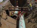 Workers lay pipe during construction of the Trans Mountain pipeline expansion on farmland in Abbotsford, B.C.