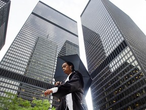 A pedestrian walks past Toronto-Dominion Bank buildings on King Street in Toronto's financial district.
