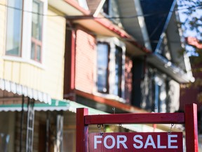 A real estate sign is displayed in front of a house in the Riverdale area of Toronto.