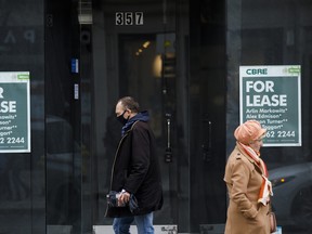 Pedestrians walk past a storefront with a 'For Lease' sign in Toronto.