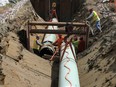 Workers lay pipe during construction of the Trans Mountain pipeline expansion on farmland in Abbotsford, B.C.