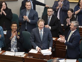 Finance and Treasury Board Minister Allan MacMaster, bottom centre, is applauded by party members while tabling the provincial budget at the Nova Scotia legislature in Halifax.