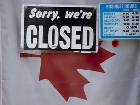 A 'closed' sign hangs in a store window in Ottawa.