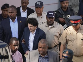 FILE - FTX founder Sam Bankman-Fried, center left, is escorted out of Magistrate Court following a hearing in Nassau, Bahamas, Dec. 19, 2022. Bankman-Fried, charged with a host of financial crimes, was arrested in the Bahamas on Dec. 12, 2022.
