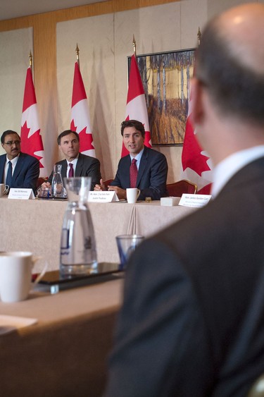 Prime Minister Justin Trudeau, right, takes part in a Long Term Investment Summit infrastructure roundtable as Minister of Finance Bill Morneau, left, looks on with international investors at Toronto's Ritz-Carlton Hotel, Nov. 14, 2016.