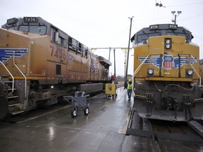 A Union Pacific worker walks between two locomotives that are being serviced in a railyard in Council Bluffs, Iowa, on Dec. 15, 2023. Recent layoffs at Union Pacific and BNSF, combined with an investment fund's campaign to take control of Norfolk Southern, are renewing concern among unions and regulators about how job cuts might affect safety and service.