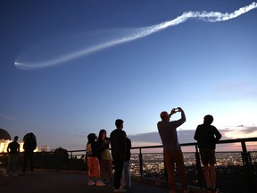 People watch a a SpaceX Falcon 9 rocket carrying a payload of 22 Starlink internet satellites into space in Los Angeles.