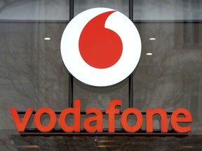 FILE - The logo of the mobile service provider 'vodafone' is pictured on the entrance of a company's store at the Kurfuerstendamm shopping boulevard in Berlin, Germany, Tuesday, Feb. 1, 2022. British cellphone company Vodafone confirmed Friday, March 15, 2024, that it is selling its Italian business to Switzerland's Swisscom for 8 billion euros ($8.7 billion) and will hand back half of the proceeds to its shareholders through the buyback of company shares.