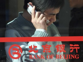 FILE - A Chinese man uses his mobile phone near the logo for the Bank of Beijing in Beijing Jan. 29, 2005. The former chairman of state-owned Bank of Beijing is under investigation for corruption, according to an official notice Friday, March 1, 2024, the latest in a series of graft investigations focused on the country's financial sector. (AP Photo, File)