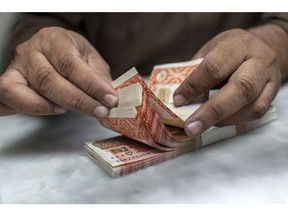 An employee counts Pakistani five thousand rupee banknotes at a cash counter of the office of Pakistan Currency Exchange Pvt in Karachi, Pakistan, on Thursday, Dec. 14, 2017. Pakistan's rupee weakened to a record low after the central bank continued to ease its grip on the currency amid mounting economic pressure and speculation that the country may need International Monetary Fund support.
