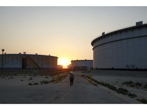 An employee walks past crude oil storage tanks at the Juaymah Tank Farm in Saudi Aramco's Ras Tanura oil refinery and oil terminal in Ras Tanura, Saudi Arabia. Photographer: Simon Dawson/Bloomberg