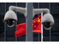The flags of China fly behind a surveillance camera outside Central Government Office in Hong Kong, China, on Tuesday, July 7, 2020. Photographer: Roy Liu/Bloomberg