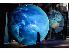 A child inspects a large-scale projection of planet earth at the Museum of Natural Sciences of Barcelona, a designated climatic refuge, part of Barcelona's Climate Shelter Network, where residents can take shelter during extreme heat.
