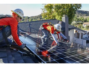 Workers install solar panels on the rooftop of a home in Poway, California. Photographer: Sandy Huffaker/Bloomberg