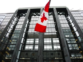 The Canadian flag flies in front of the Bank of Canada in Ottawa. Deloitte says Canada is set to avoid a recession.