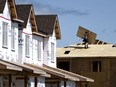 HomeStars' annual Reno Report for 2023 found the average household spend on renovations was $12,300, down from $13,000 in 2022 and forecast to fall to $10,264 this year. A builder carries a sheet of wood on the roof of a home in a new subdivision in the Ottawa suburb of Kanata, Ont., Friday, July 30, 2021.