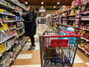 A person checks prices as she shops in her local grocery store using a calculator in Montreal, Wednesday, March 27, 2024. 