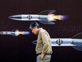 A man walks past a banner depicting missiles along a street in Tehran this month. For the first time in history, Israel and Iran have attacked each other directly.