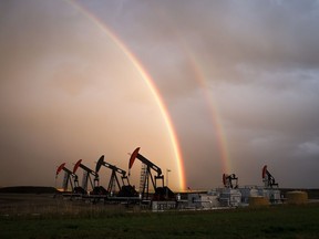 A rainbow appears to come down on pumpjacks
