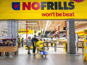 A customer pushes a shopping cart full of groceries from a No Frills grocery store in Toronto.