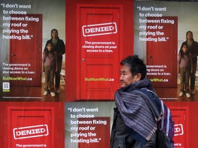 A pedestrian walks past posters stating ButNowWhat.ca which is presented by the non-prime members of the Canadian Lenders Association on Toronto's Queen Street.