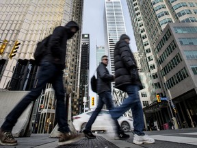 Pedestrians walk across Front Street at Bay Street in Toronto’s Financial District.