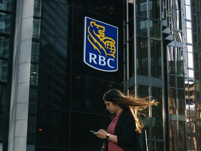 A woman walks past a Royal Bank of Canada sign in the financial district in Toronto.
