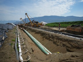 Workers lay pipe during construction of the Trans Mountain pipeline expansion on farmland in Abbotsford, B.C., 2023.