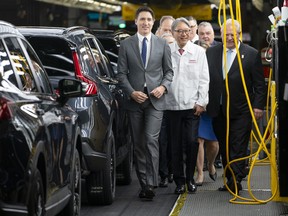 Prime Minister Justin Trudeau, left, alongside Honda Global head Toshihiro Mibe, centre, and Ontario Premier Doug Ford, right, tours the manufacturing line at the Honda of Canada Manufacturing Plant 2 in Alliston, Ont.