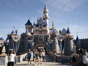 FILE - Visitors pass through Disneyland in Anaheim, Calif., April 30, 2021.