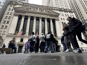 FILE - People walk past the New York Stock Exchange March 27, 2024. Global shares are trading higher on Monday, April 29, 2024, amid optimism over the rally that ended the week on Wall Street, although eyes are on the Federal Reserve policy meeting set for later this week.