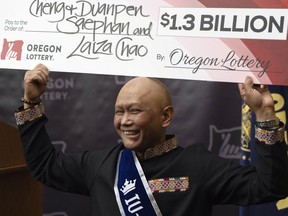 Cheng "Charlie" Saephan holds a check above his head after speaking during a news conference where it was revealed that he was one of the winners of the $1.3 billion Powerball jackpot at the Oregon Lottery headquarters on Monday, April 29, 2024, in Salem, Ore.
